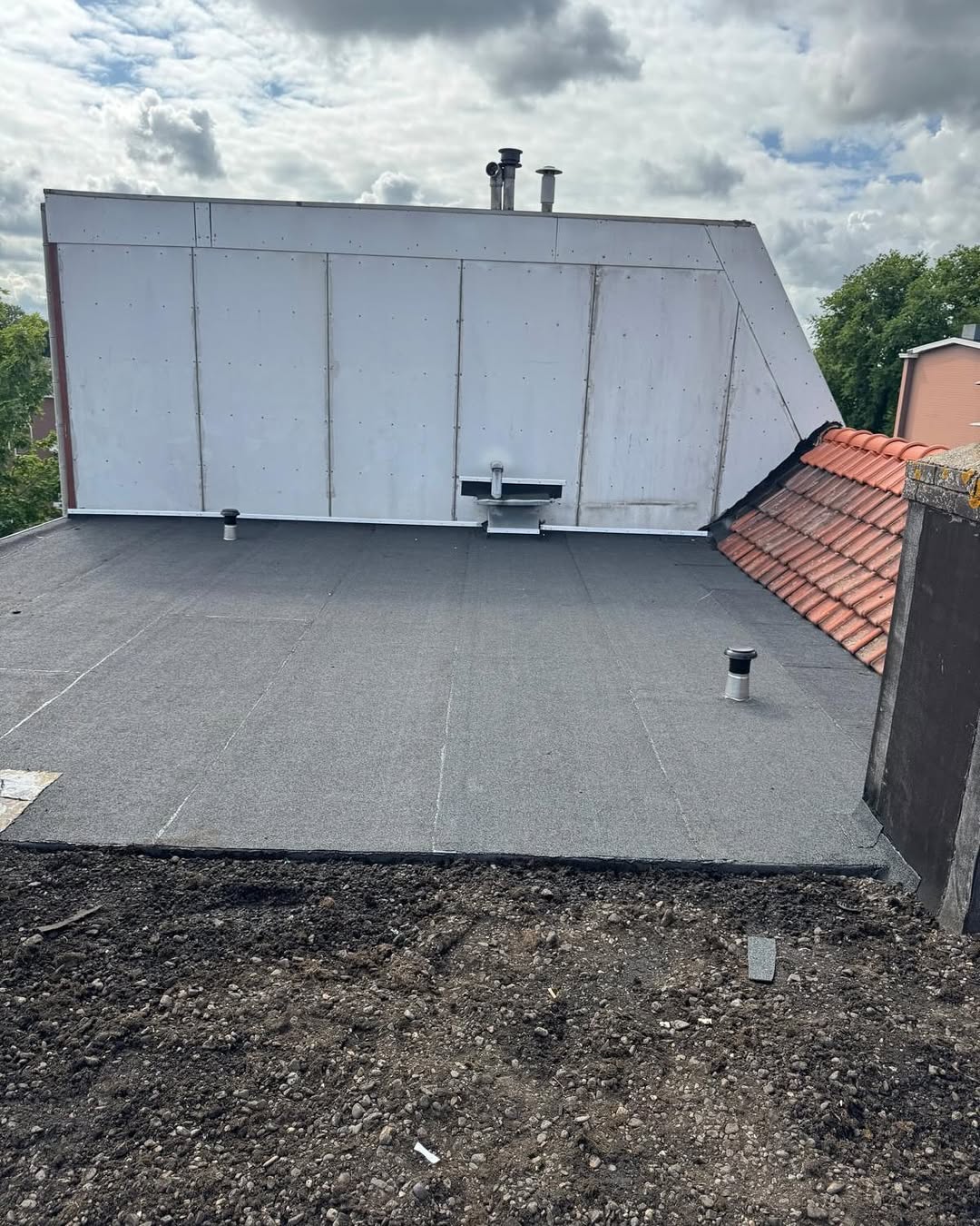 Vakmanschap - afgewerkt plat dak naast pannendak